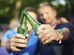 Closeup image of two guys toasting their beer bottles at a music festival