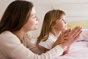 Mother and daughter praying in bed
