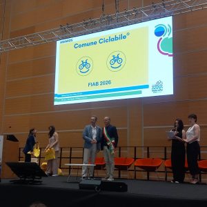 Il consigliere Gianluigi Serena durante la cerimonia di consegna della Bandiera Gialla FIAB ComuniCiclabili 2026, riconoscimento ottenuto da Porto Recanati per l'impegno nella mobilità sostenibile.